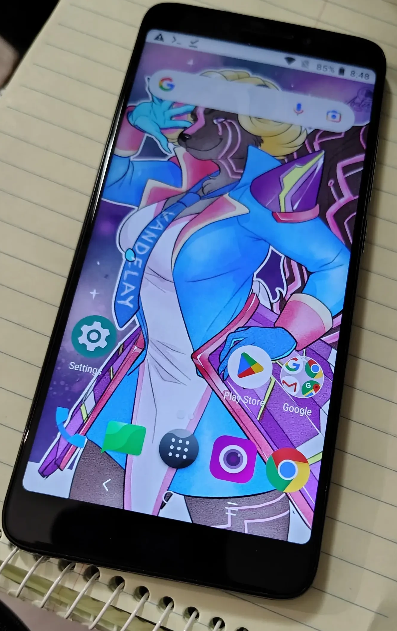 A photograph of the Alcatel 7, a perfectly boring budget Android smartphone from 2018. It's unlocked. The wallpaper features my fursona, a skunk with black and pink circuit stripes wearing this tight blue jacket with sharp metal bits on the hips and shoulders. She's dressed as Mimosa from Hi-Fi Rush if that means anything to you. Drawn by the darling https://www.sunset-aria.com/.
